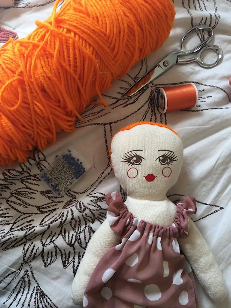 orange yarn and sewing supplies with a rag doll