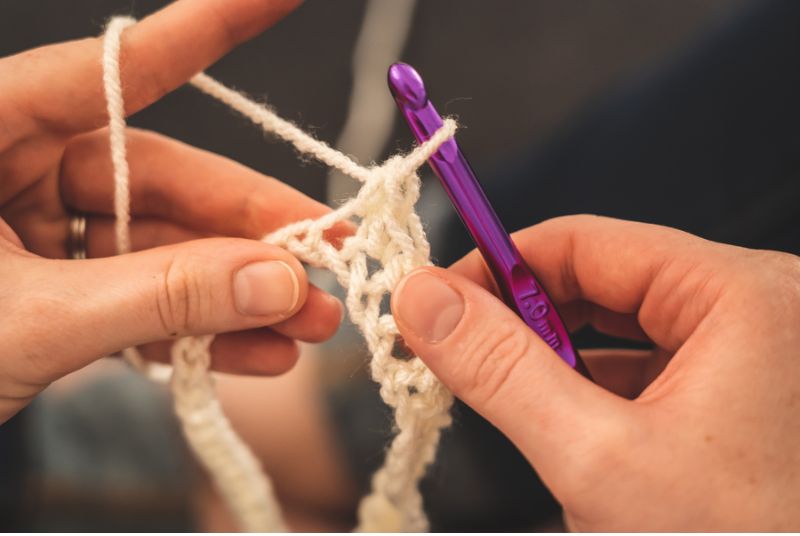 hands and crochet hook with white yarn