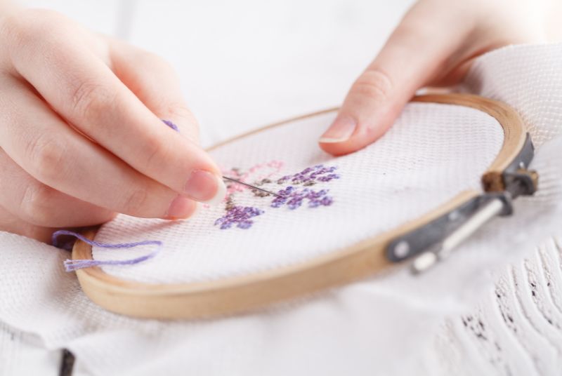 woman's hands embroidering flower with a hoop