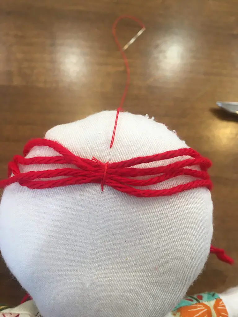 first pieces of yarn sewn onto doll head