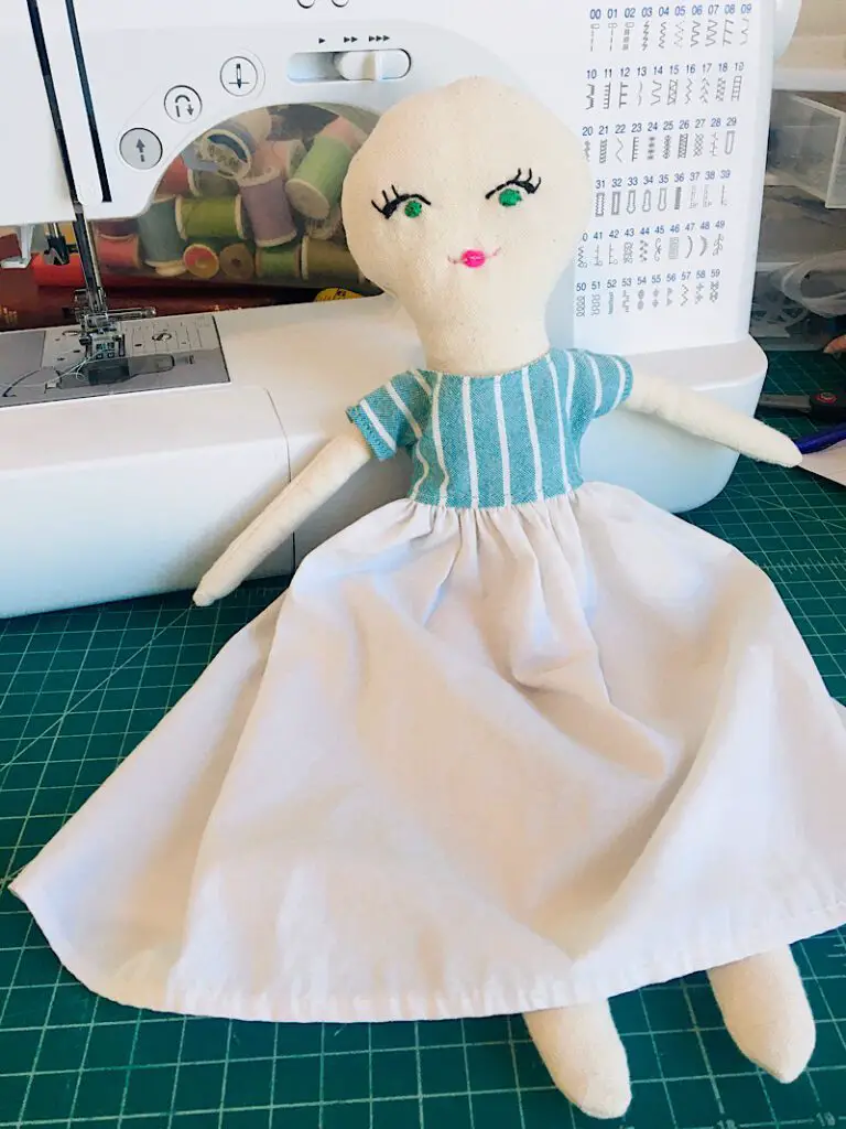 cloth doll in a fabric dress by sewing machine