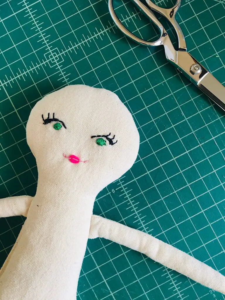 Embroidered mouth and lips on a cloth doll on table with scissors