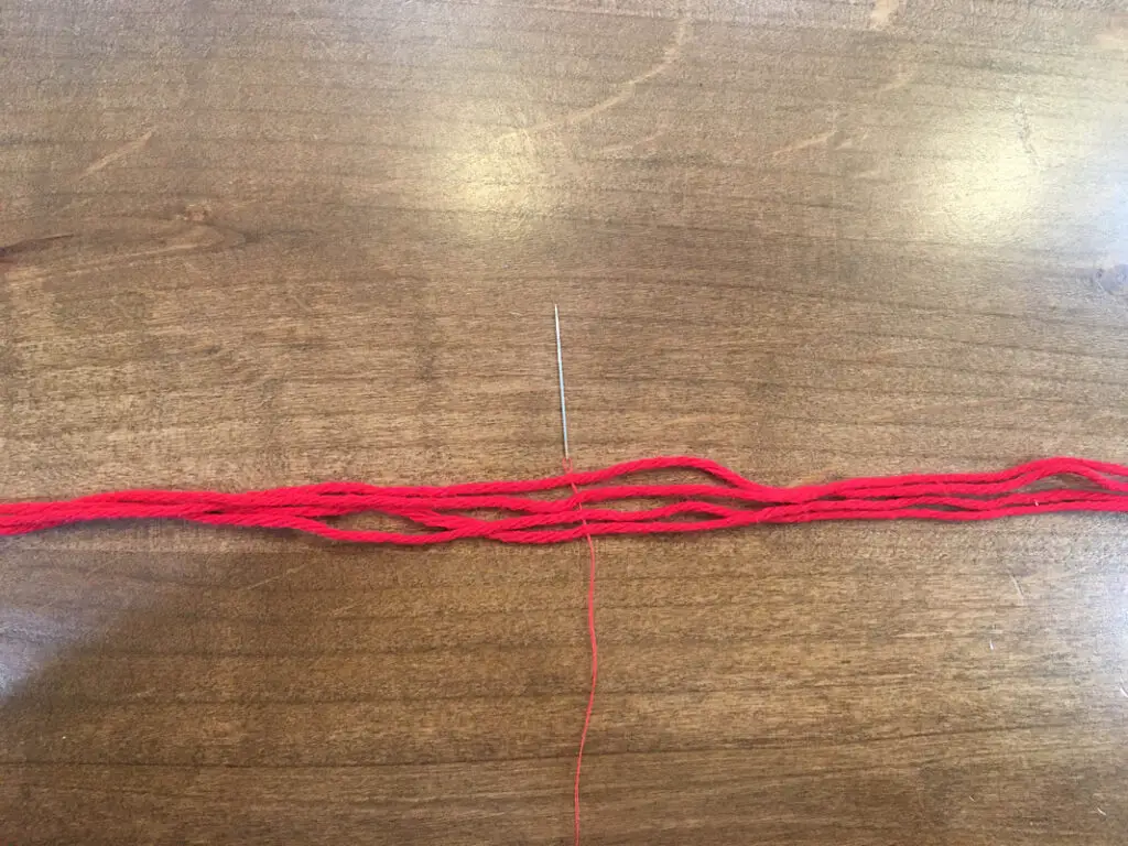 sew the thread through 4 strands of red yarn