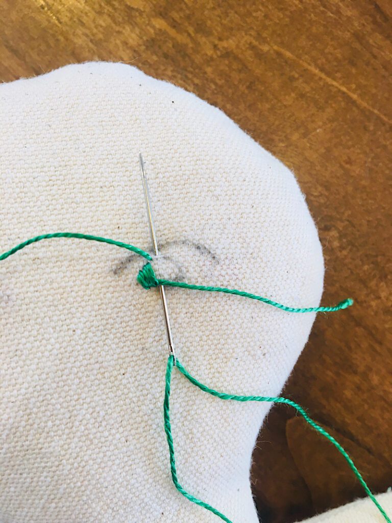 making satin stitches with green embroidery floss