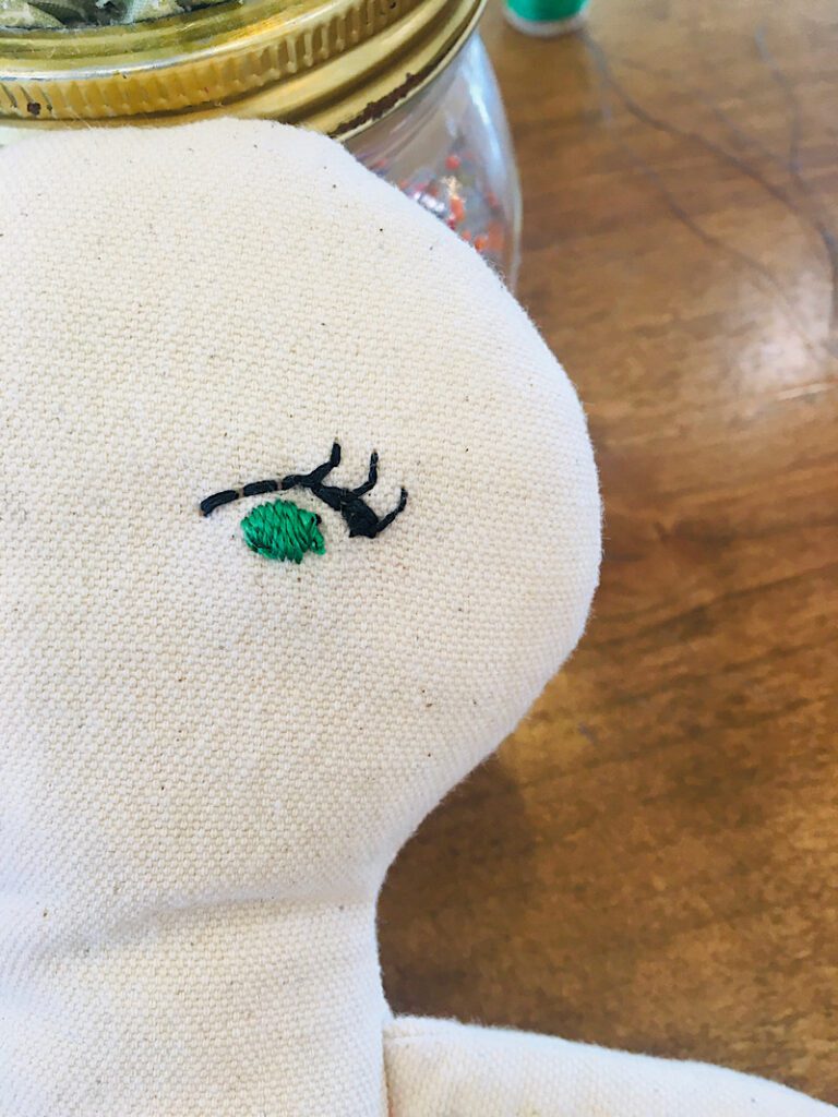 embroidering the eyelashes on a doll