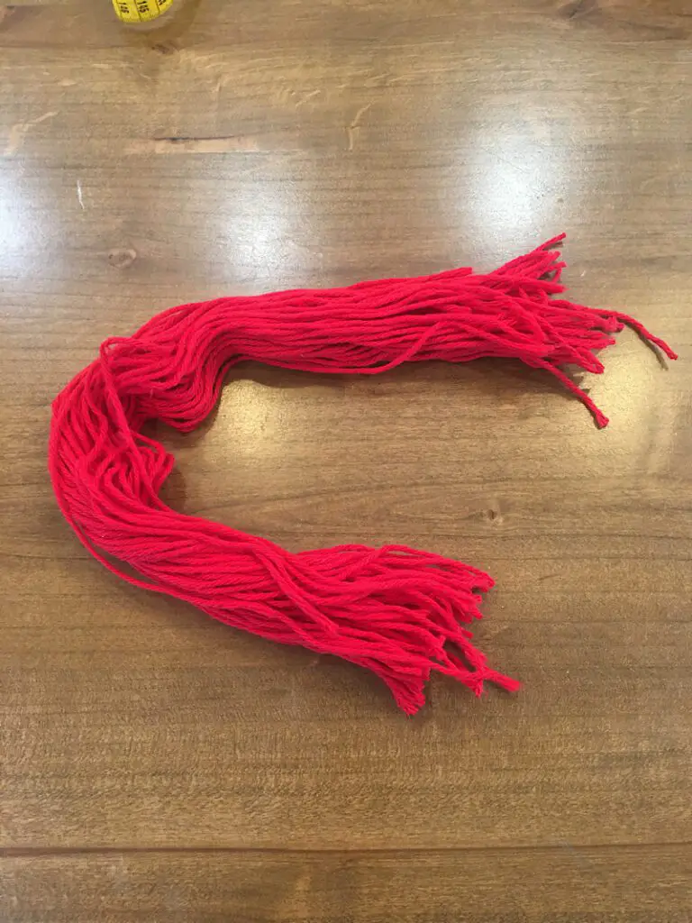 cut red yarn 20 inches long for doll hair