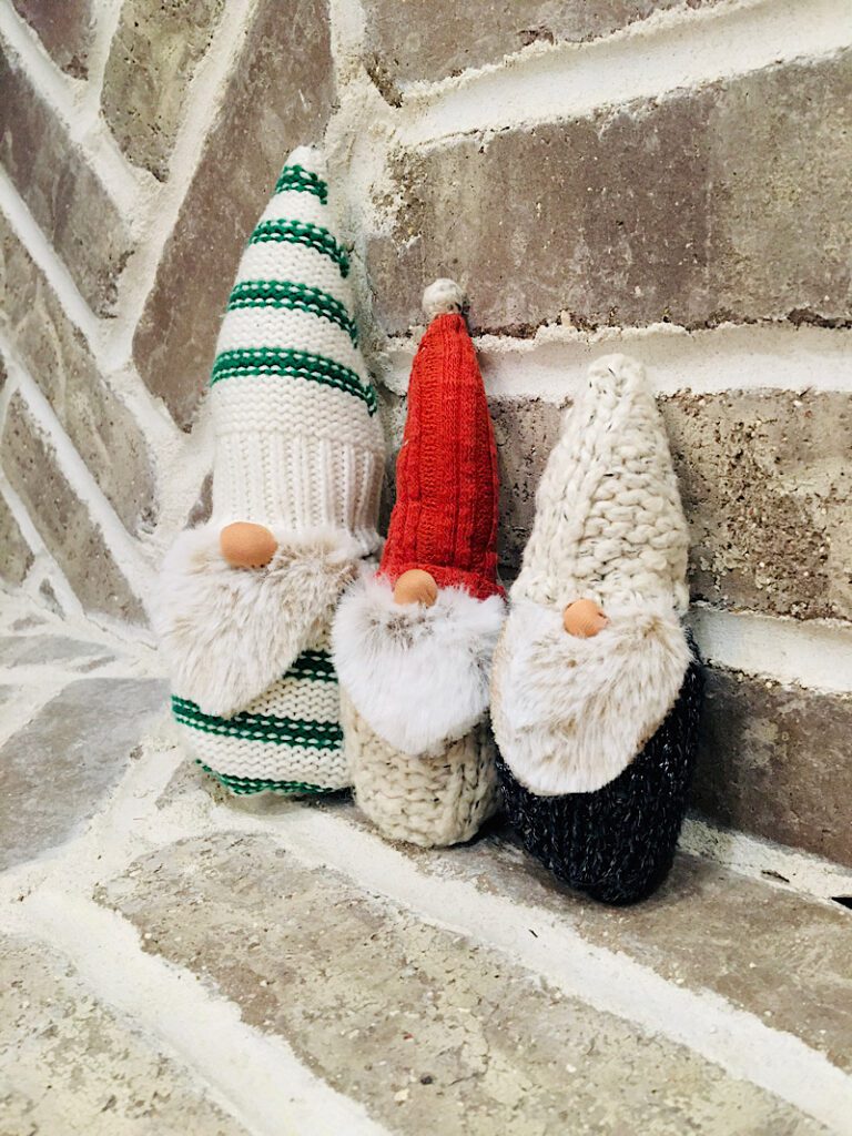 three sweater gnomes on a brick christmas hearth