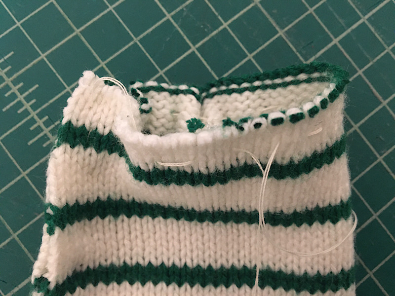 sewing a baste stitch around the bottom edge of the sweater 