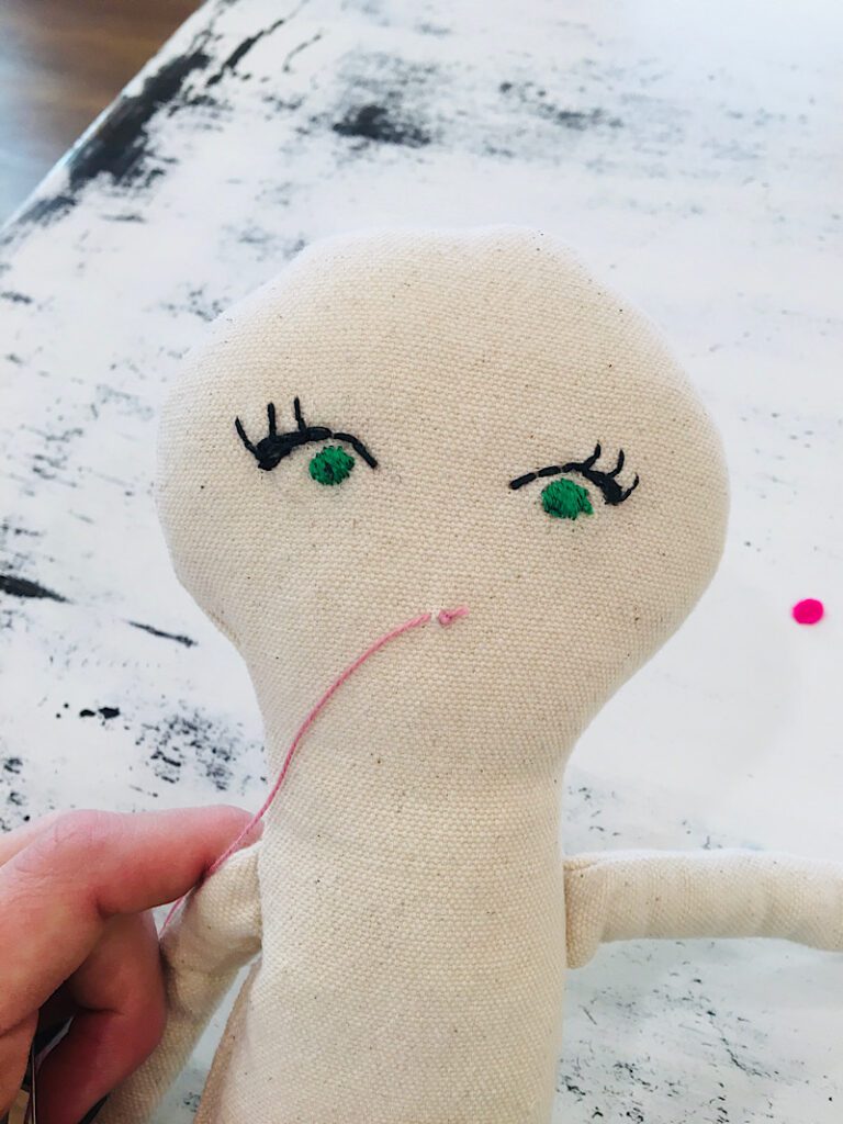 embroidering the first stitch in the doll