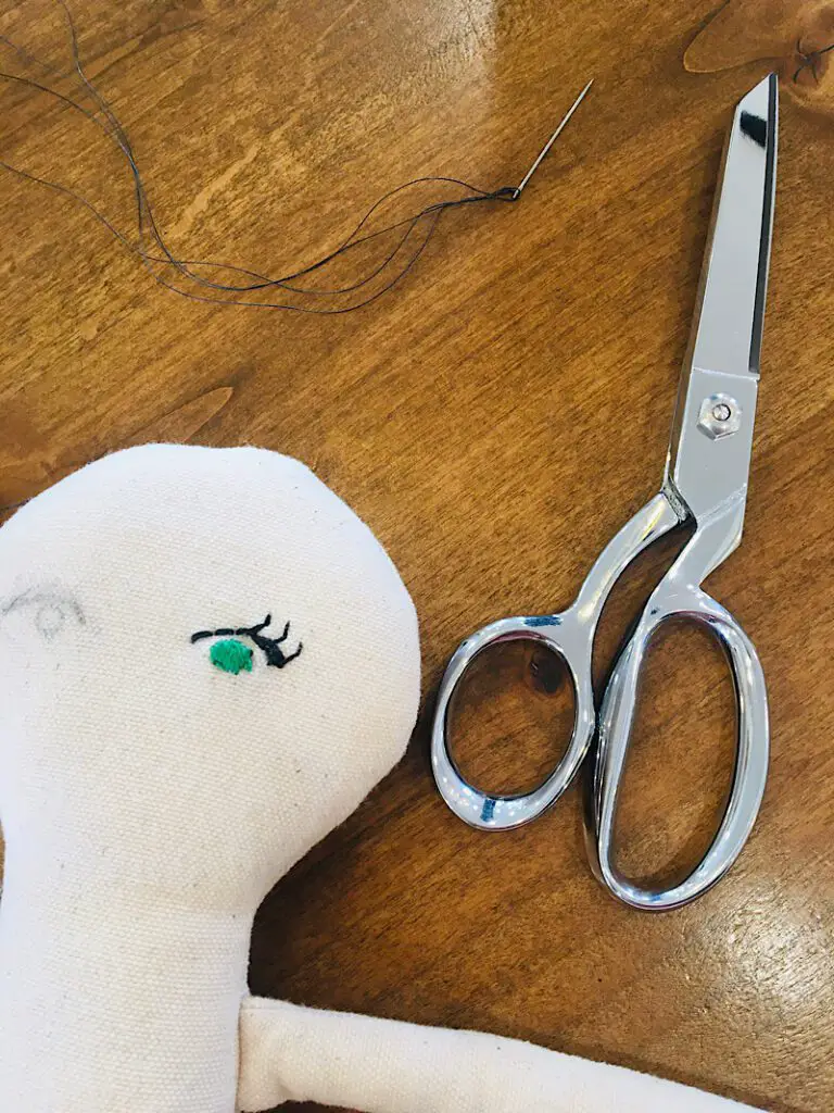 embroidered green doll eye on doll with scissors