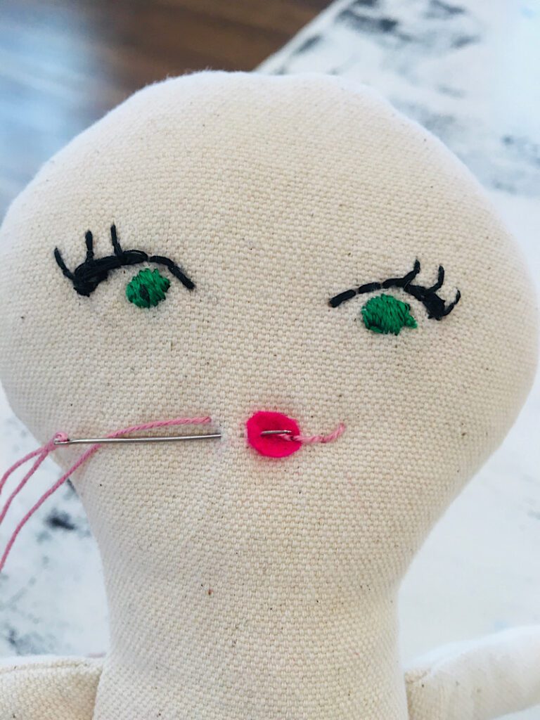 embroidering the left side of the mouth on the doll
