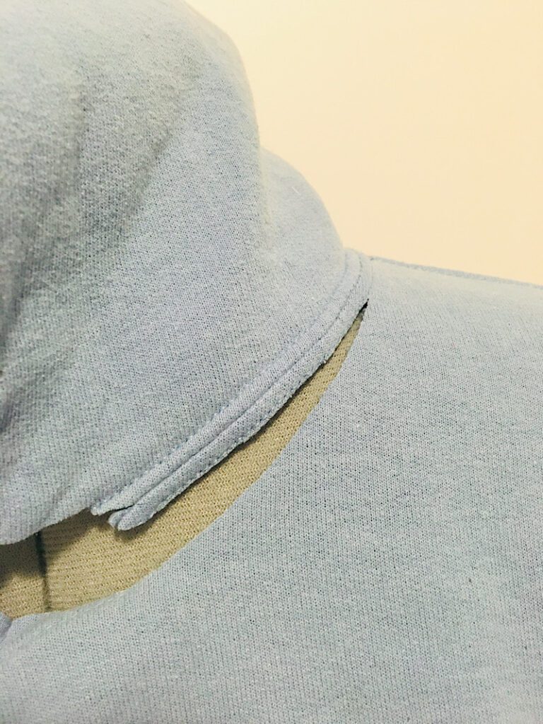 cutting off the hood of a hoody along the coverstich line