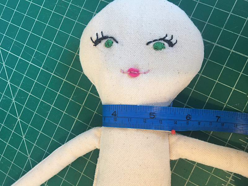 measuring around a dolls neck with a blue tape