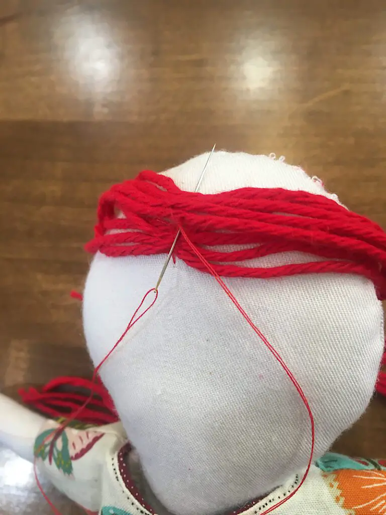 sewing yarn hair on a doll 