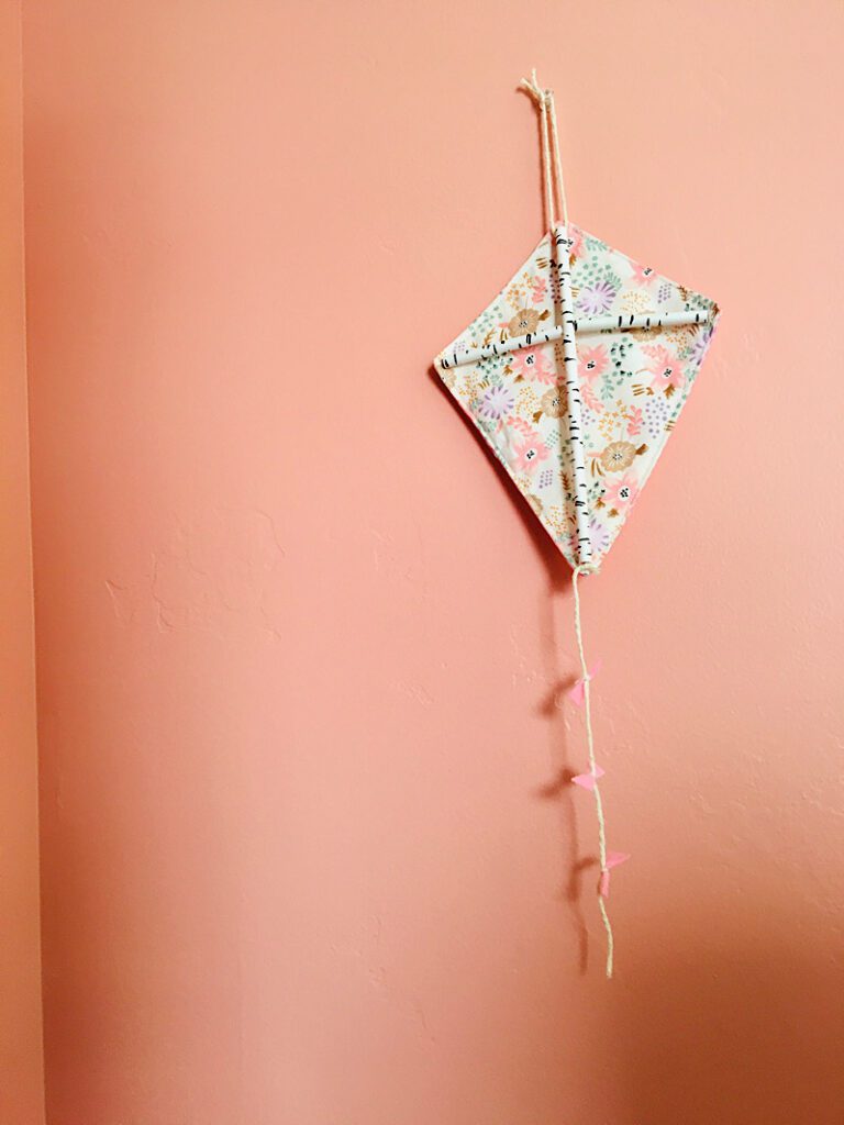 Decorative fabric kite hanging on a pink wall
