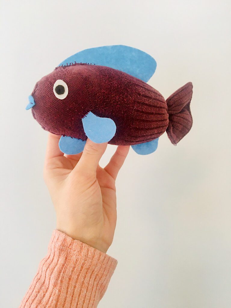 woman's hand holding a plush fish toy 