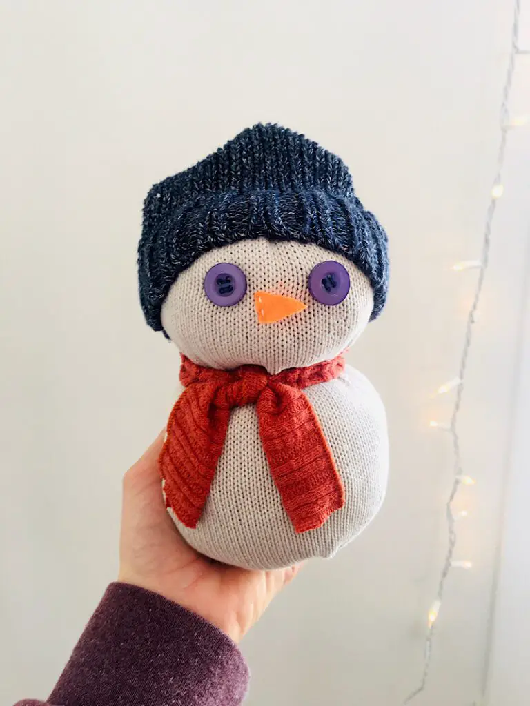 holding a snowman made from sweaters