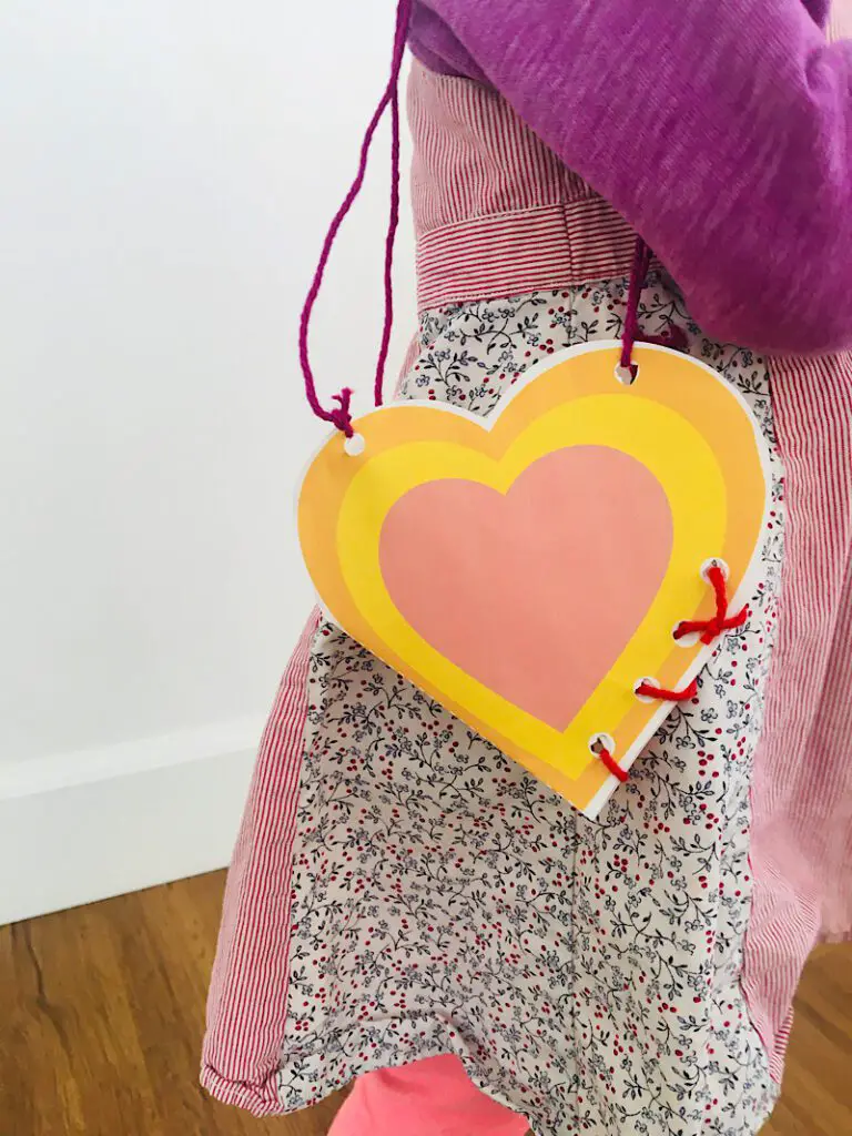 toddler wearing a paper heart purse