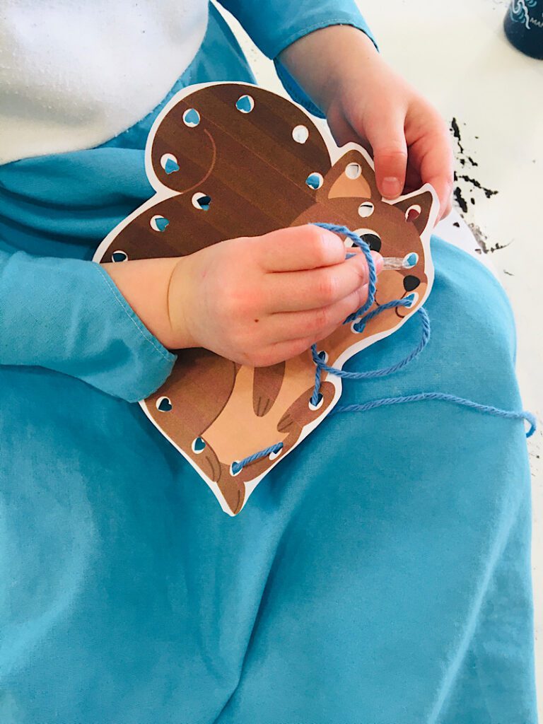 toddler threading a squirrel lacing card