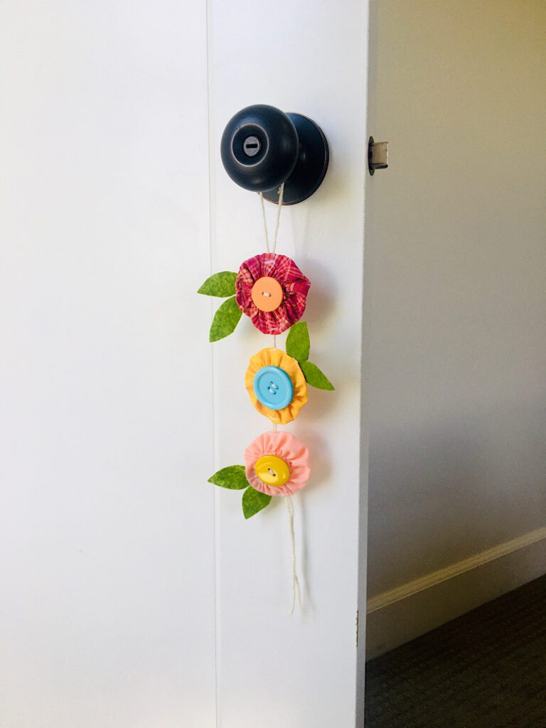 fabric yoyo flowers decor project hanging on a doorknow