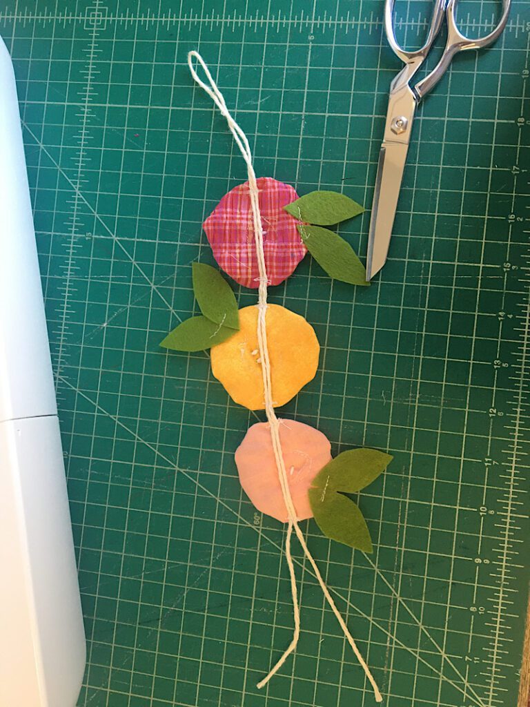 attaching the fabric yoyo flowers to a string