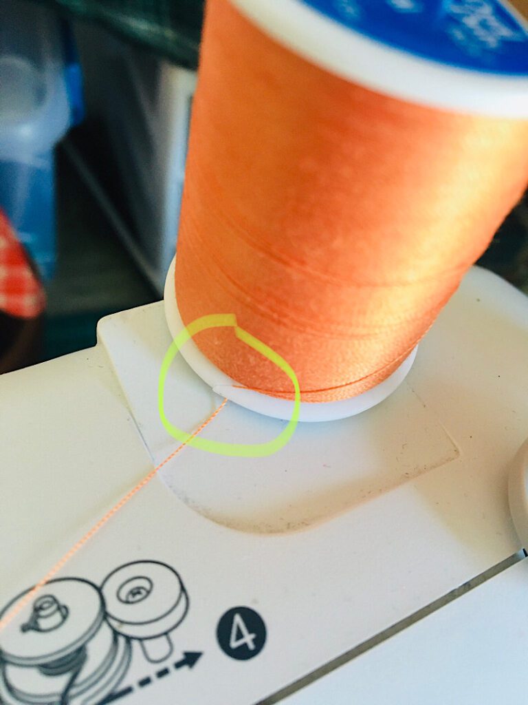 thread caught on slit of spool on sewing machine causing it to unthread