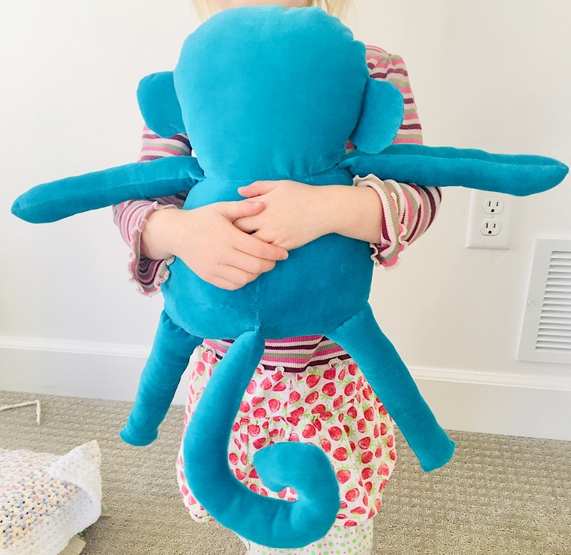 girl holding a blue stuffed monkey