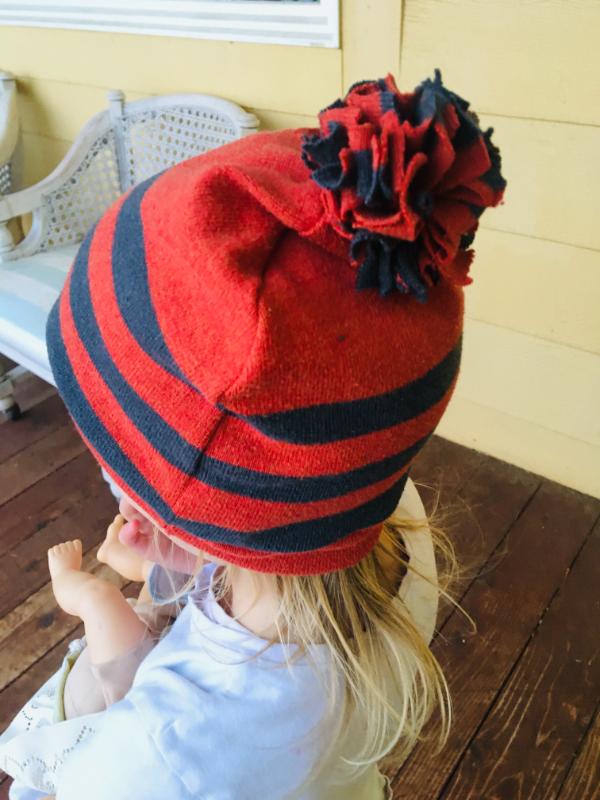 A girl wearing an orange striped beanie that was made from a sweater